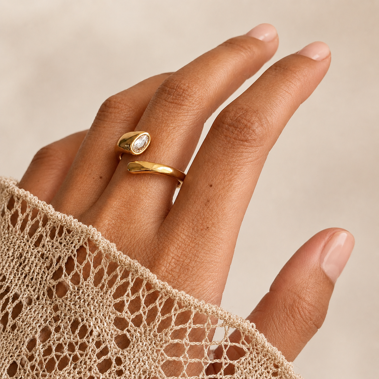 Aero Ring i 316 kirurgiskt stål och 18k PVD-guld, en öppen guldfärgad ring med klar oval sten buren på hand mot ljus neutral bakgrund.
