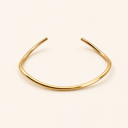 Drift Cuff i 316 kirurgiskt stål och 18k PVD-guld, ett öppet guldfärgat cuff-armband mot ljus neutral bakgrund.
