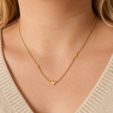 Ember Necklace i 316 kirurgiskt stål och 18k PVD-guld, ett guldfärgat halsband med små hjärtdetaljer buret på halsen.