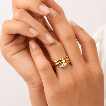 Maris Ring i 316 kirurgiskt stål och 18k PVD-guld, en guldfärgad ring med klar sten buren i lager på hand mot ljus neutral bakgrund.