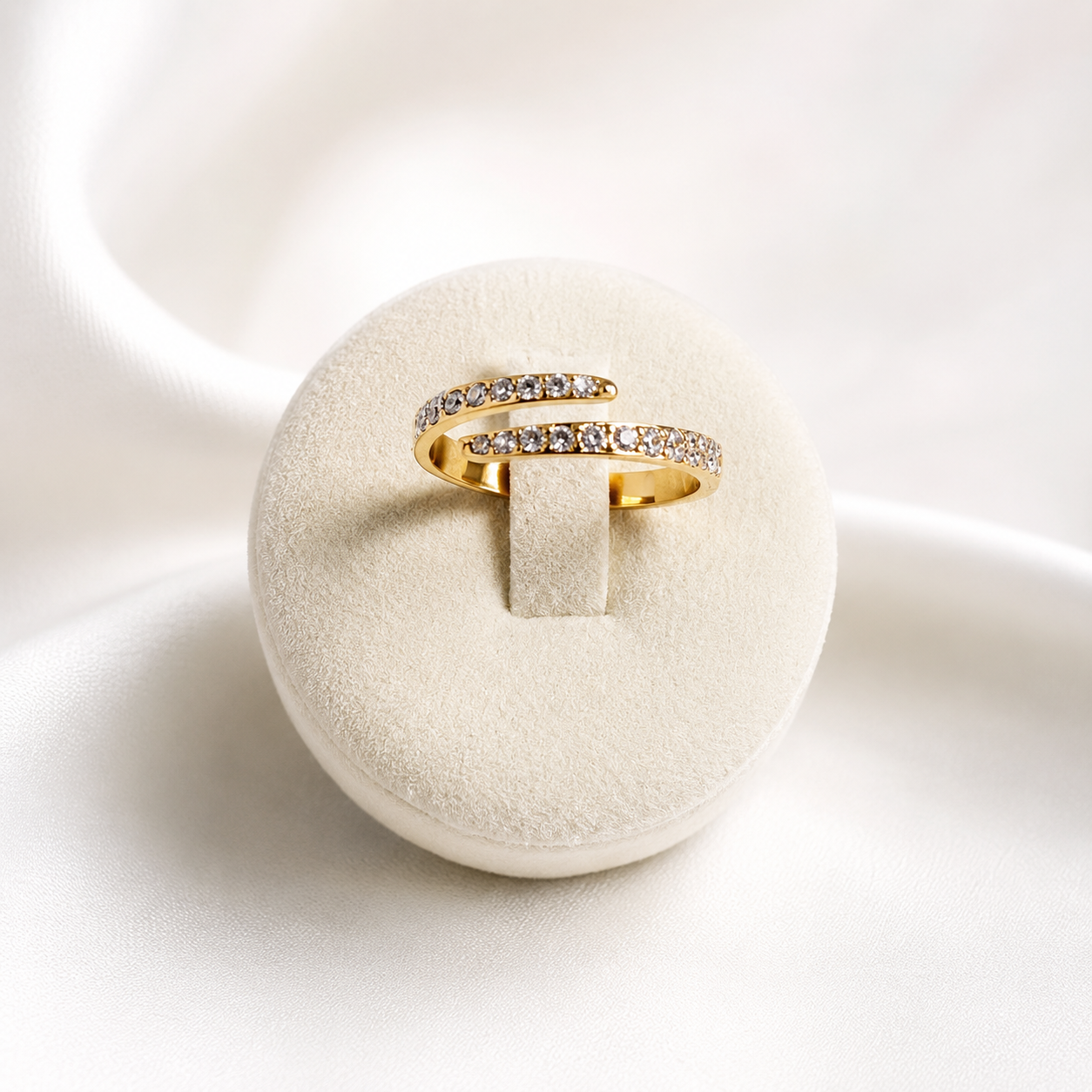 Orbit Ring i 316 kirurgiskt stål och 18k PVD-guld, en öppen guldring med klara stenar på vit smyckeshållare mot ljus neutral bakgrund.