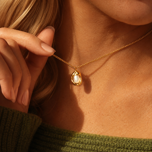 Oyster Necklace i 316 kirurgiskt stål och 18k PVD-guld, närbild på guldfärgat halsband med pärldetalj buret vid halsen.