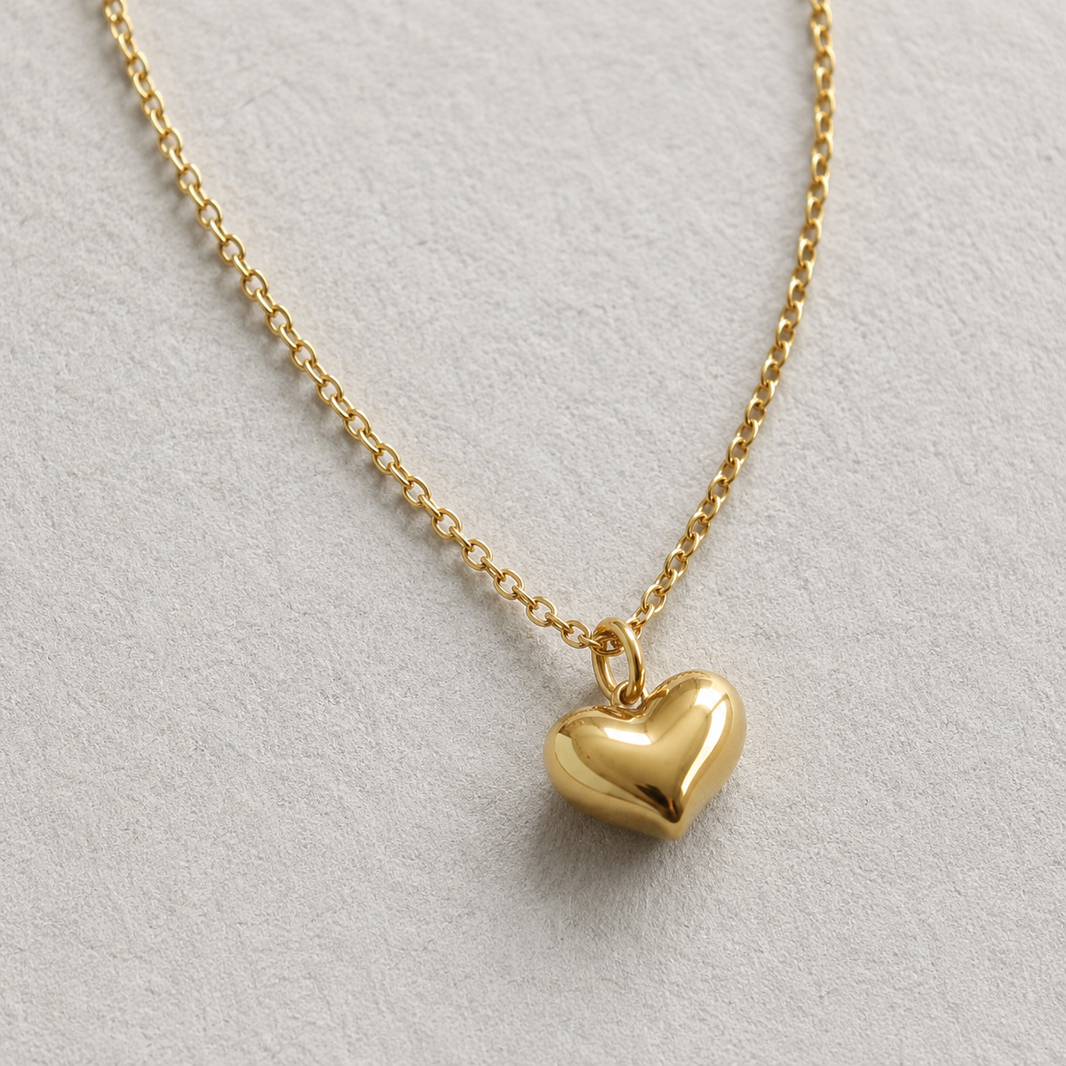 Pulse Necklace i 316 kirurgiskt stål och 18k PVD-guld, närbild på guldfärgat halsband med rundat hjärthänge mot ljus neutral bakgrund.