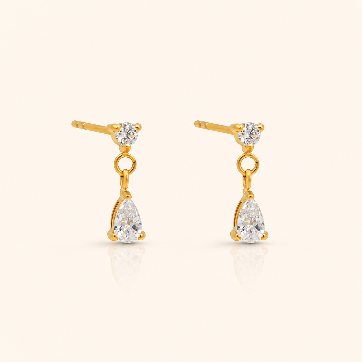 Cascade Stud örhängen i 18k PVD-guld med rund zircon och hängande droppformad zircon på ljus bakgrund