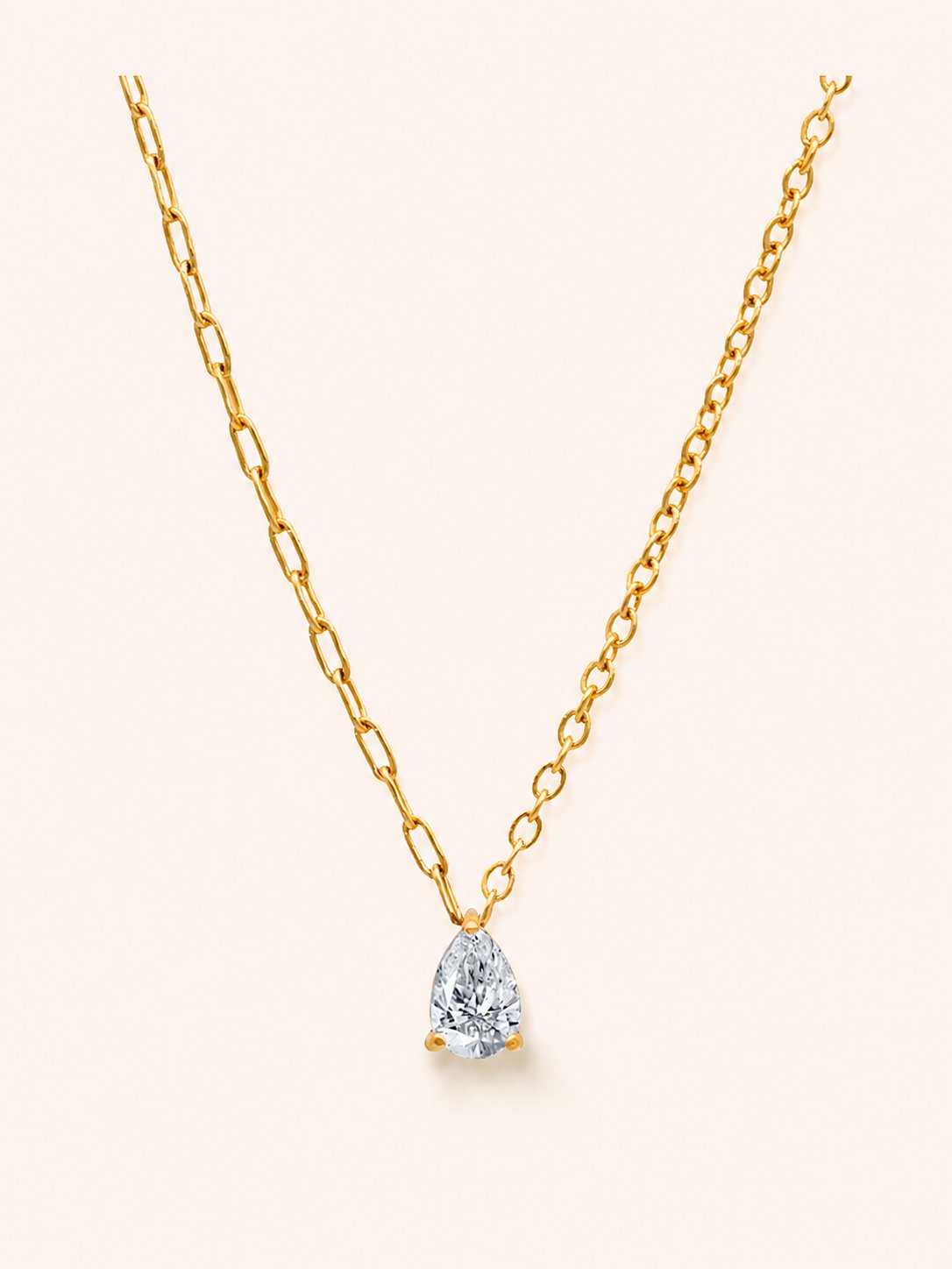 Drop Necklace i 18k PVD-guld med droppformad zircon och asymmetrisk kedja på ljus bakgrund
