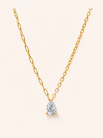 Drop Necklace i 18k PVD-guld med droppformad zircon och asymmetrisk kedja på ljus bakgrund