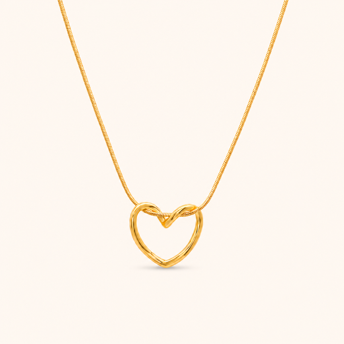 Echo Necklace i 18k PVD-guld med öppet hjärtformat hänge och snake chain på ljus bakgrund.