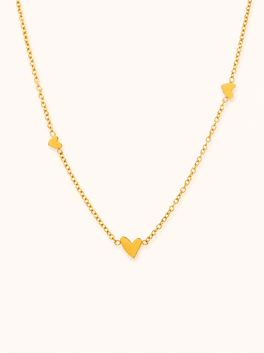 Ember Necklace i 18k PVD-guld med små hjärtdetaljer på ljus bakgrund