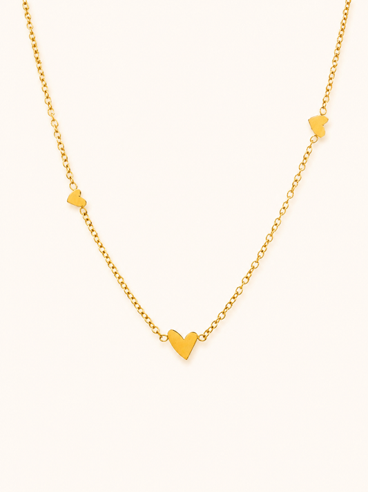 Ember Necklace i 18k PVD-guld med små hjärtdetaljer på ljus bakgrund