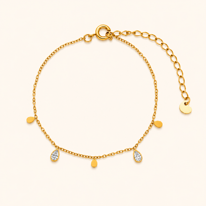 Glimmer Bracelet i 18k PVD-guld med droppformade detaljer och zircon på ljus bakgrund