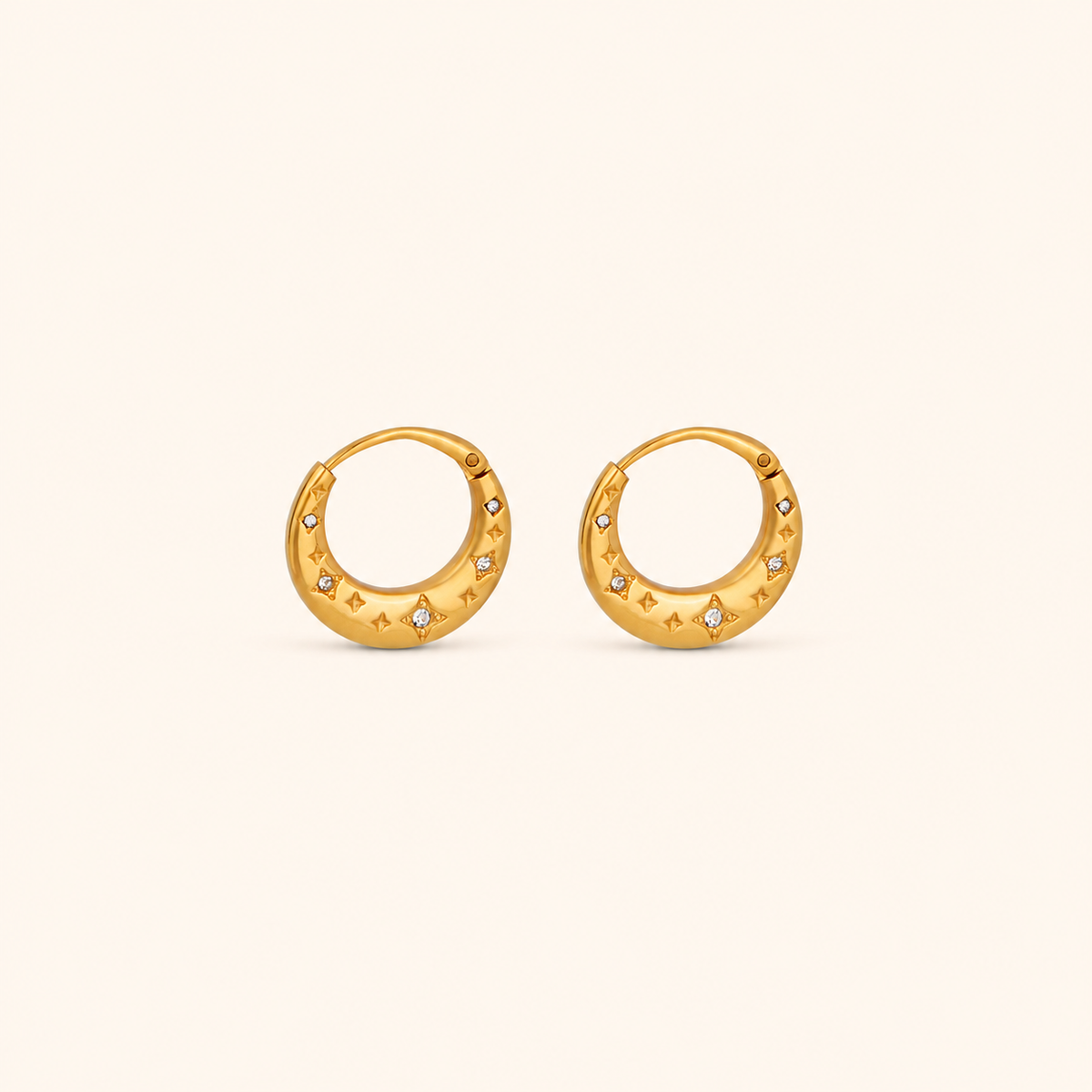 Nova Hoop huggieörhängen i 18k PVD-guld med stjärndetaljer och små zircon på ljus bakgrund.
