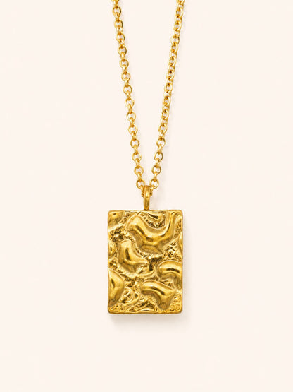 Relief Necklace i 18k PVD-guld med rektangulärt texturerat hänge på ljus bakgrund