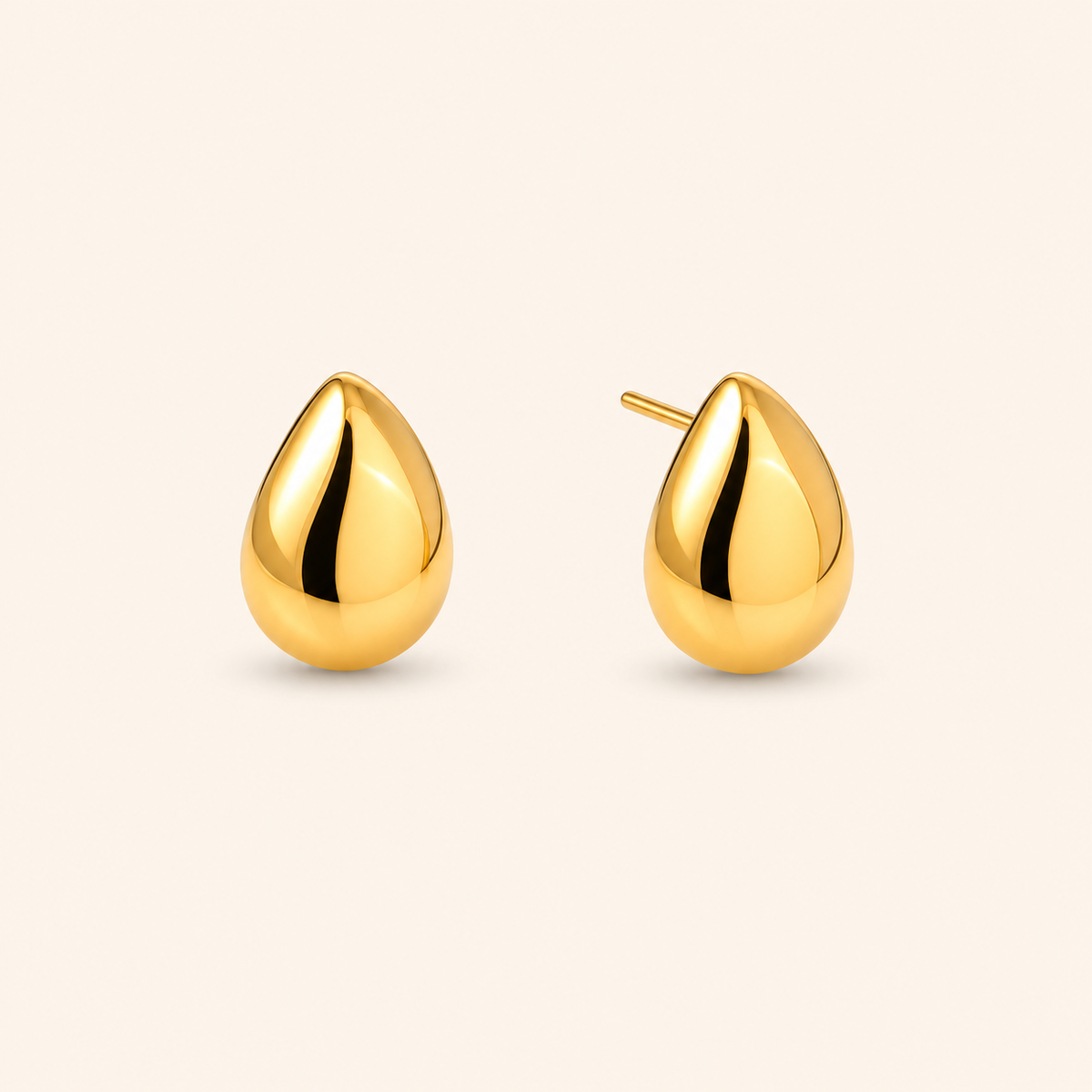 Stone Stud örhängen i 18k PVD-guld med teardropform på ljus bakgrund