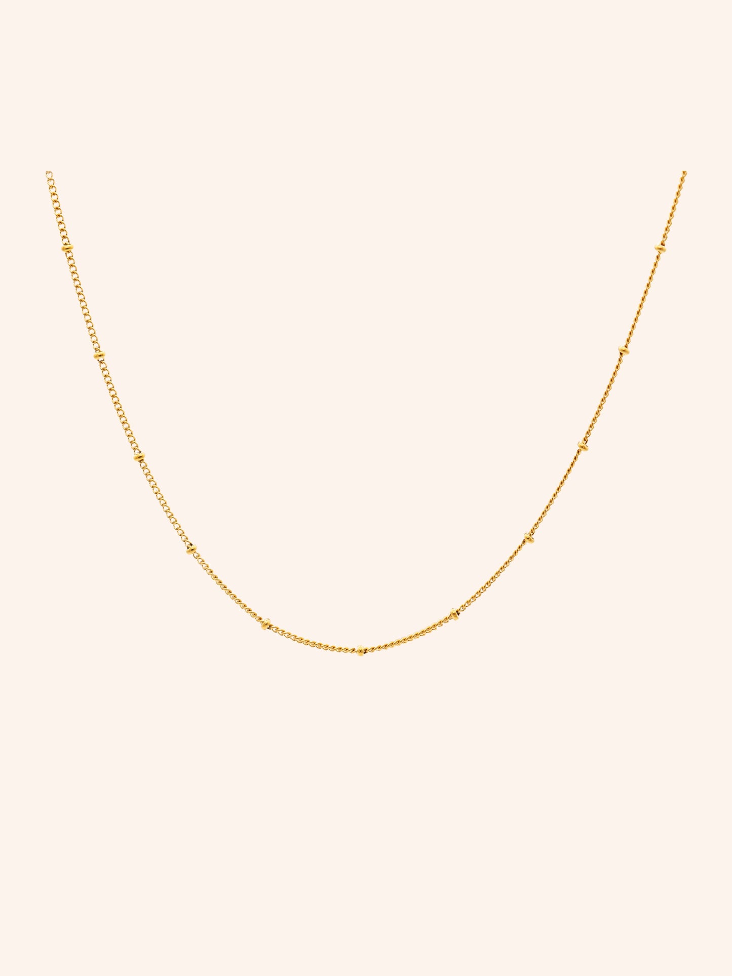 Tether Necklace i 18k PVD-guld med små detaljer längs kedjan på ljus bakgrund