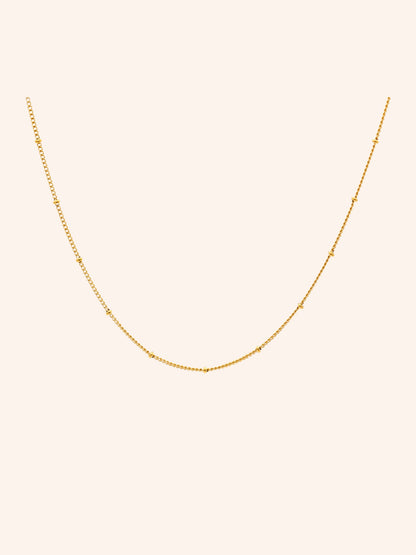 Tether Necklace i 18k PVD-guld med små detaljer längs kedjan på ljus bakgrund
