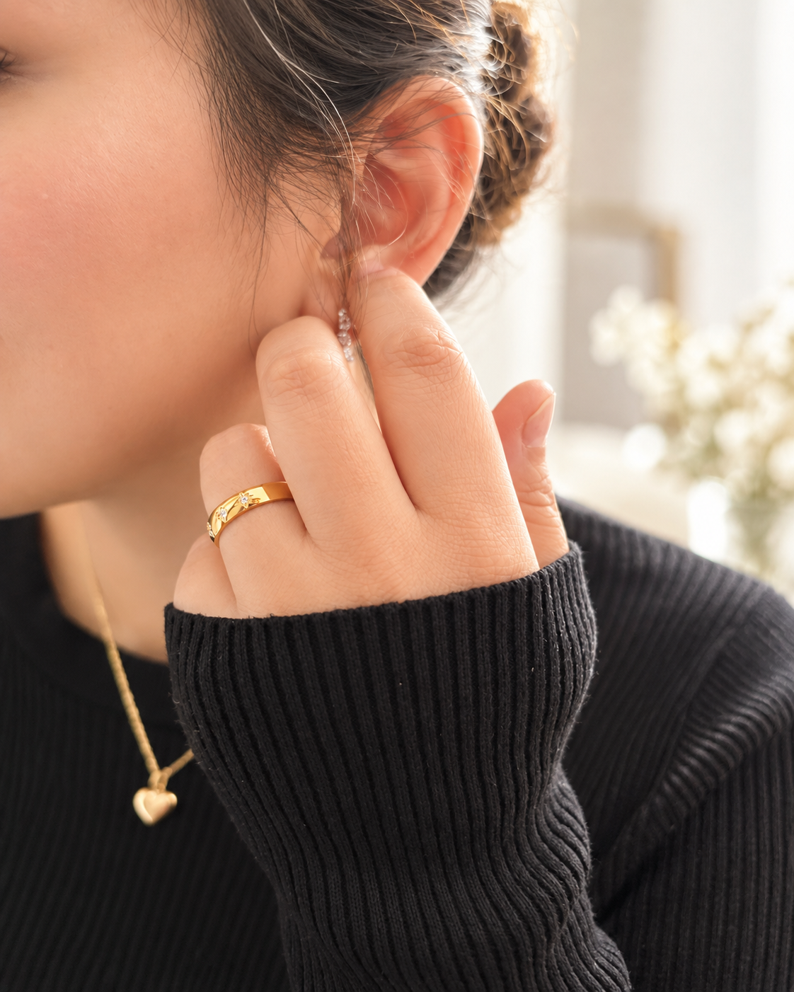 Sol Ring i guld med stjärndetaljer och klara stenar buren på hand i varmt dagsljus.