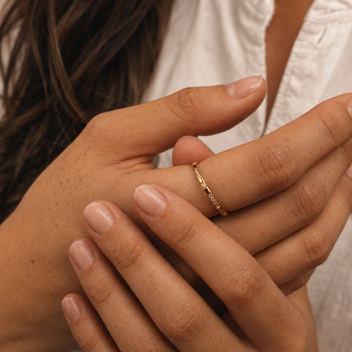 Spark Ring på hand, smal guldfärgad ring med diskreta klara stenar.