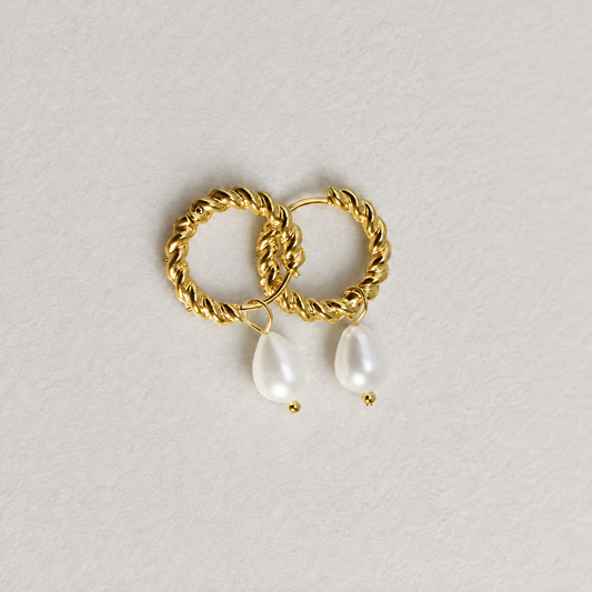 Tide Pearl Hoop i 316 kirurgiskt stål och 18k PVD-guld, tvinnade guldfärgade hoops med pärldroppar mot ljus neutral bakgrund.