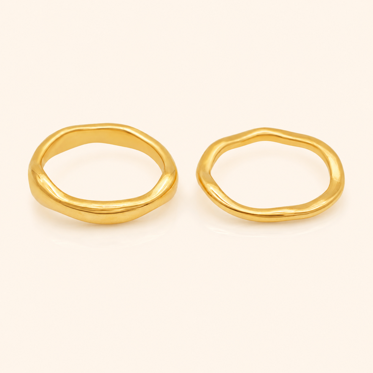 Trace Ring 2-pack i 316 kirurgiskt stål och 18k PVD-guld, två mjukt formade guldringar mot varm neutral bakgrund.