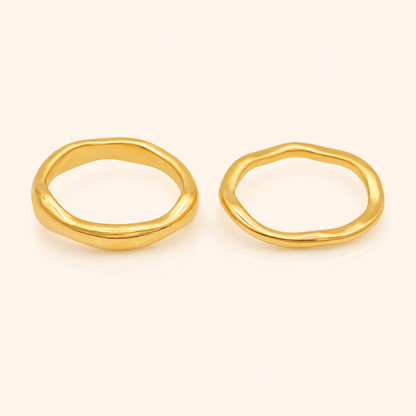 Trace Ring 2-pack i 316 kirurgiskt stål och 18k PVD-guld, två mjukt formade guldringar mot varm neutral bakgrund.