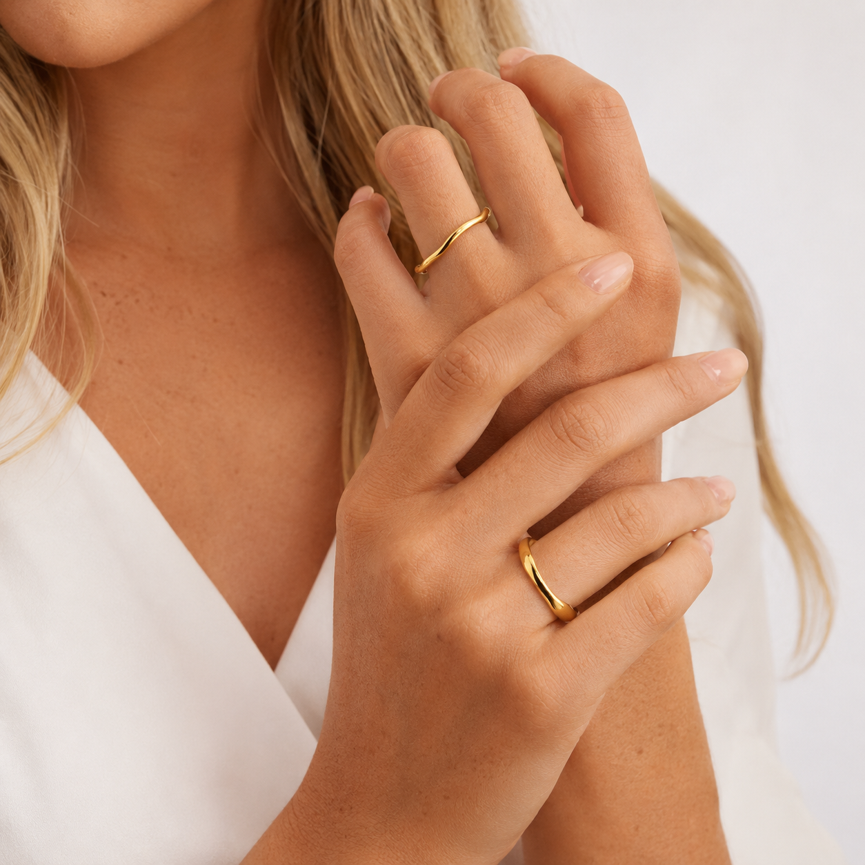 Trace Ring 2-pack i 316 kirurgiskt stål och 18k PVD-guld, två mjukt formade guldringar burna på händer mot vit textil.
